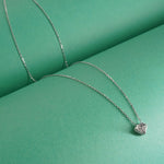 92.5 sterling Silver necklace with a diamond pendant on a green surface