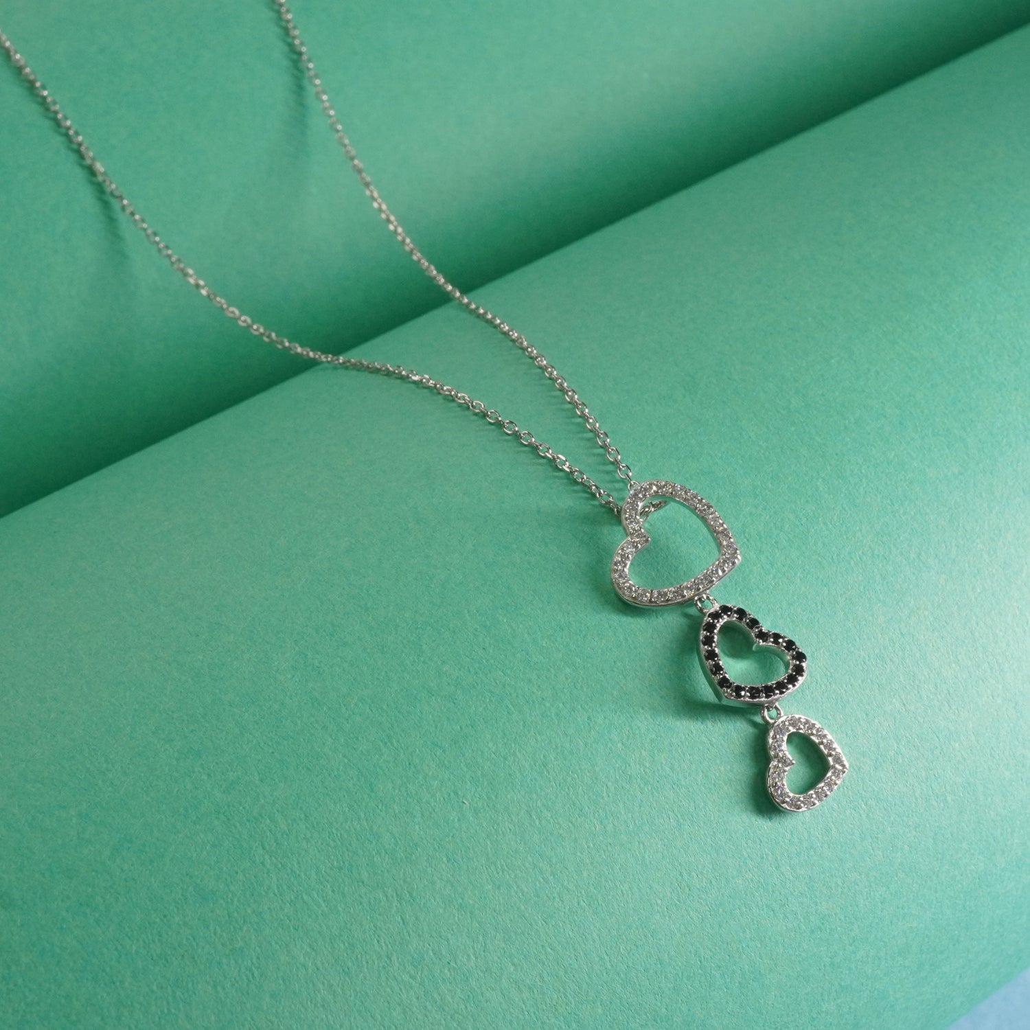 Sterling Silver necklace with heart-shaped pendants on a green background