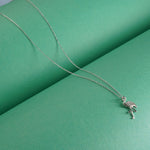 Silver necklace with a flamingo pendant on a green background