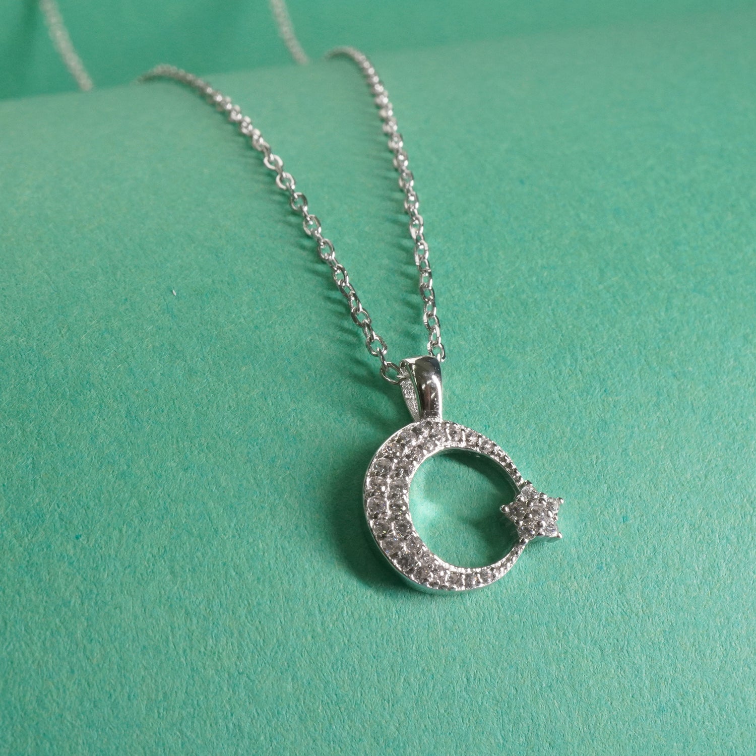 sterling Silver necklace with a crescent moon pendant on a green background