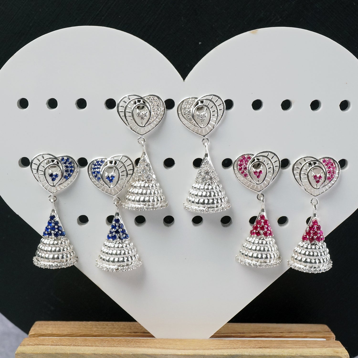 3 photos of silver jhumka designs with ad stones.