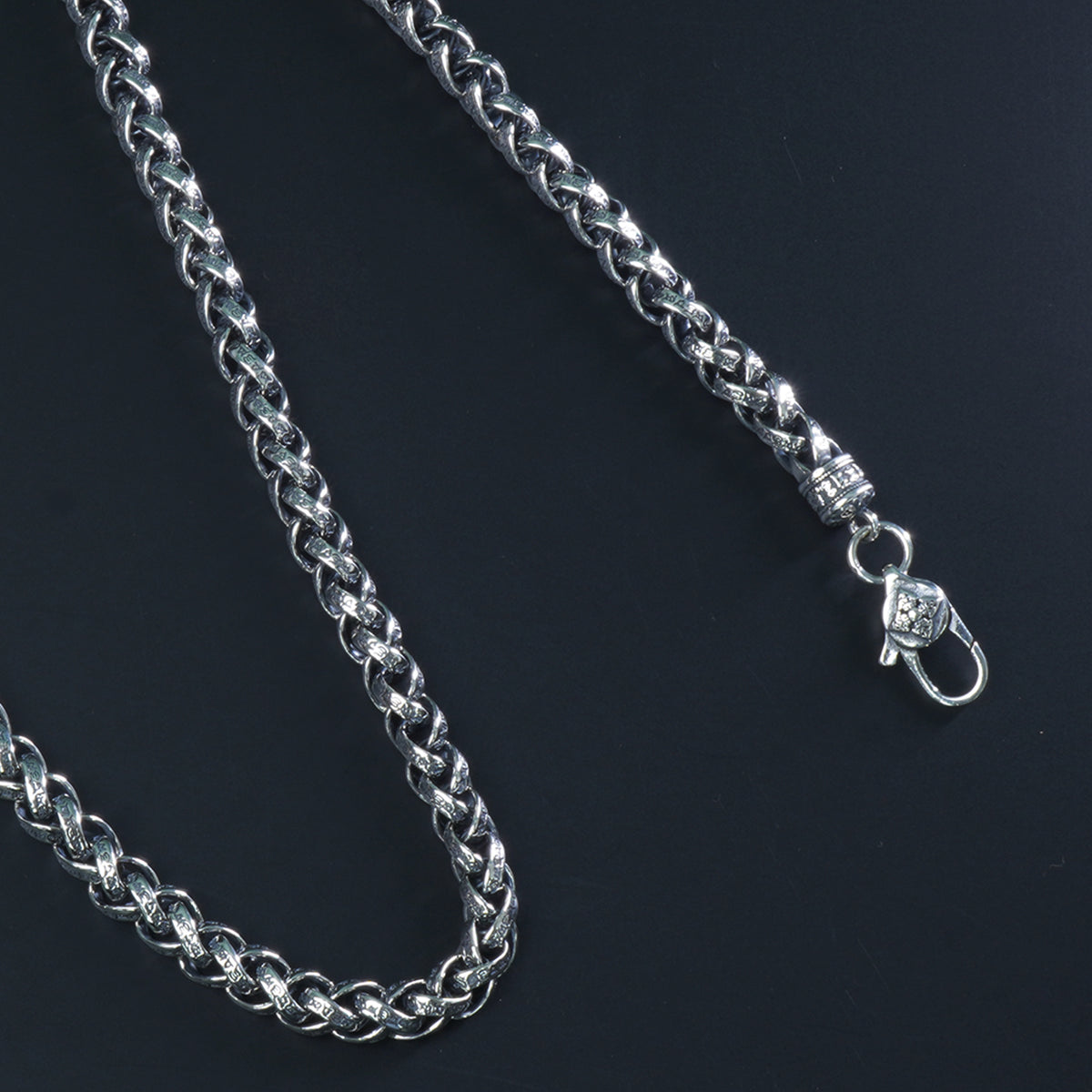 Close-up of intertwined engraved Cuban links in 925 silver chain

