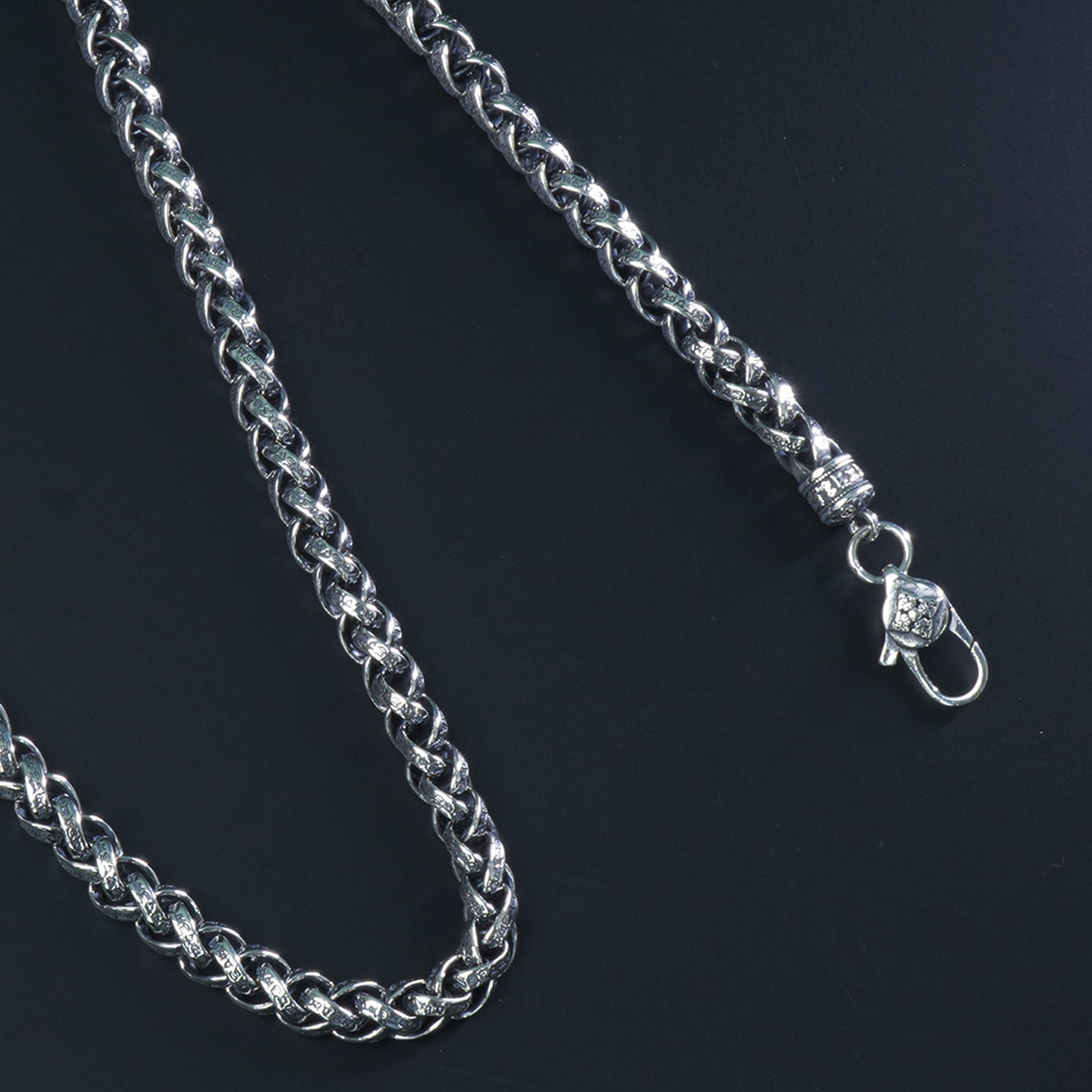 Close-up of intertwined engraved Cuban links in 925 silver chain

