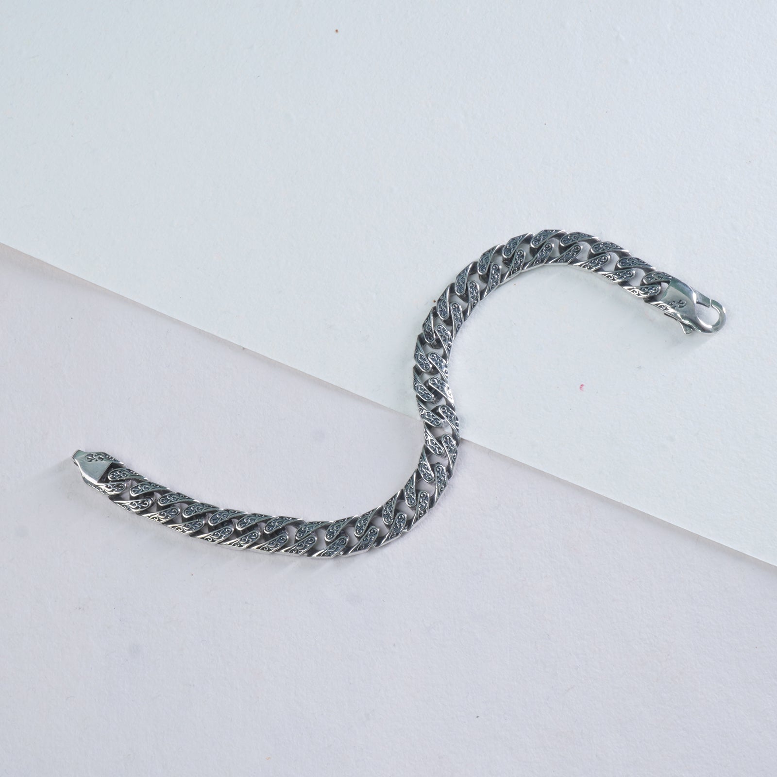 Silver chain bracelet on a light gray background