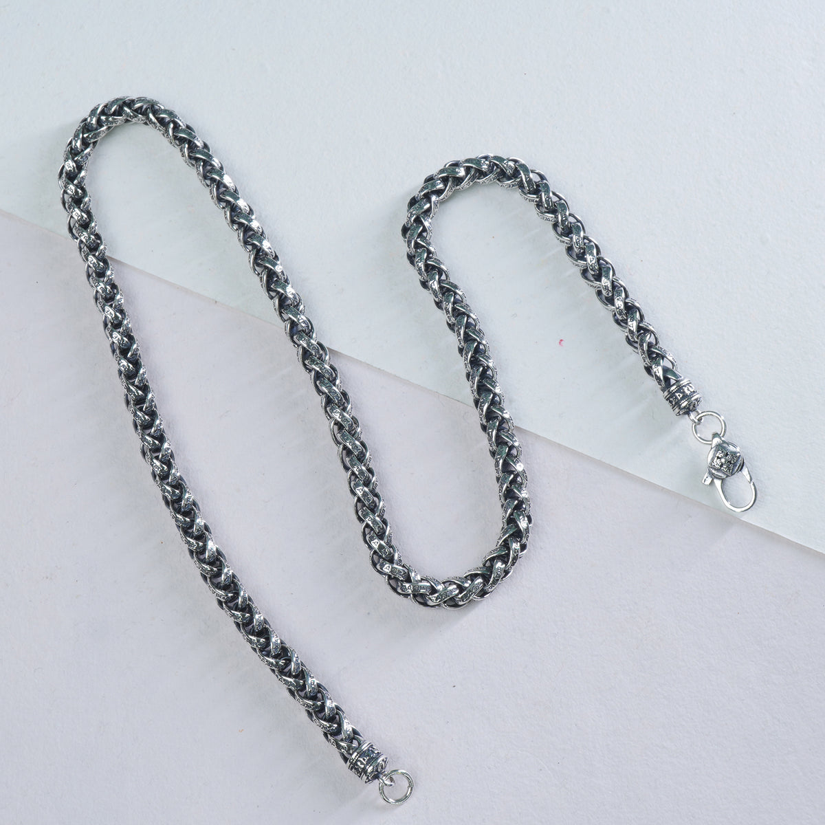 Silver mens chain necklace on a light gray background