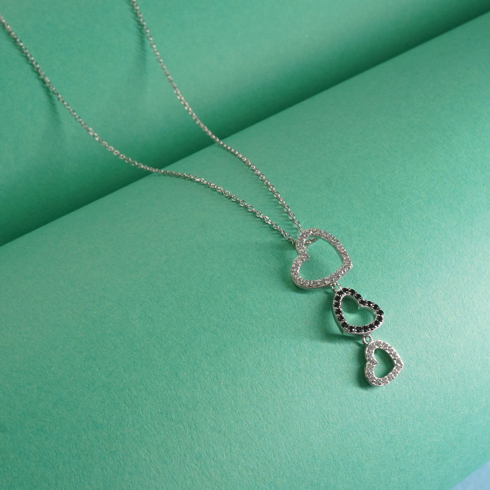 Sterling Silver necklace with heart-shaped pendants on a green background