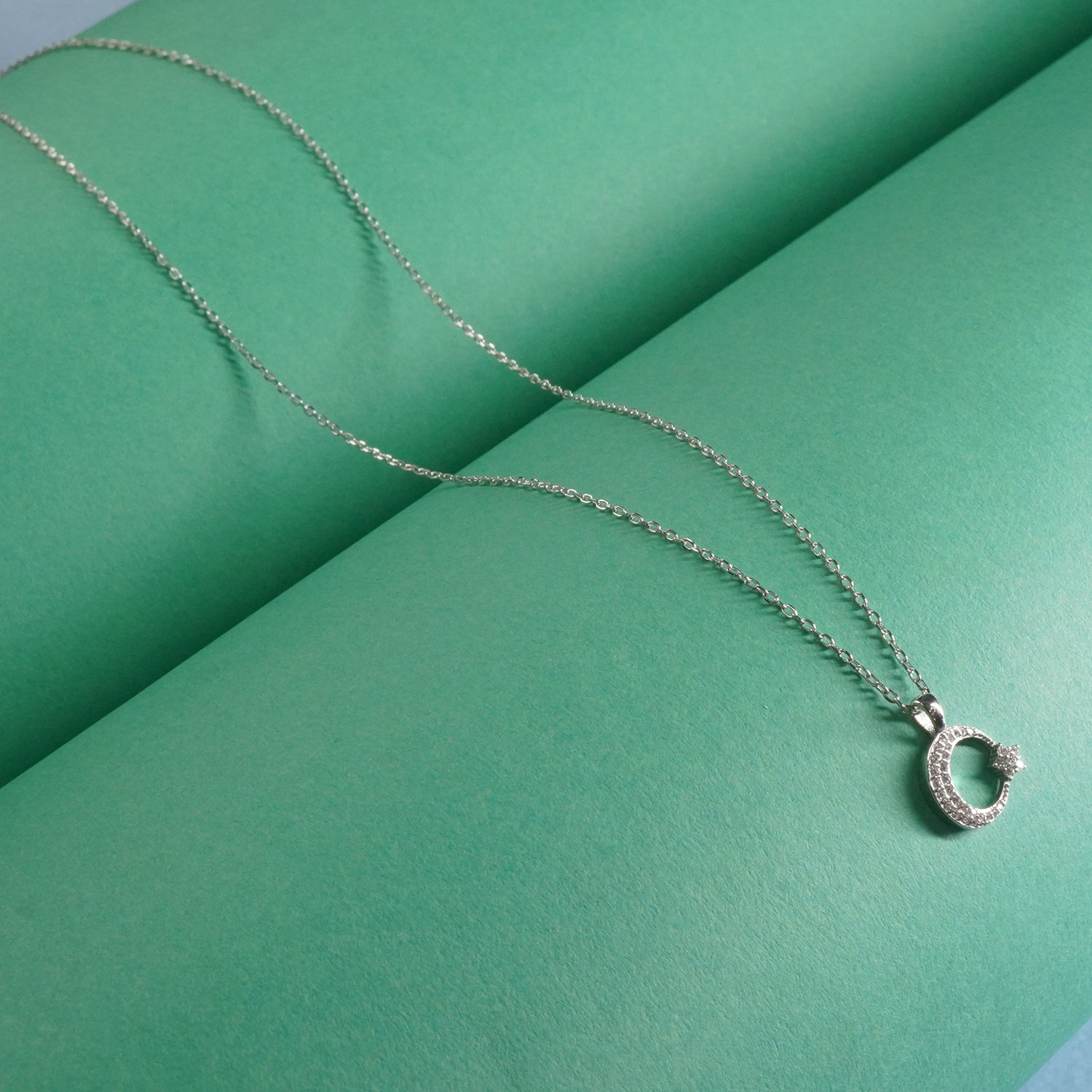 Sterling Silver necklace with moon star pendant on a green surface