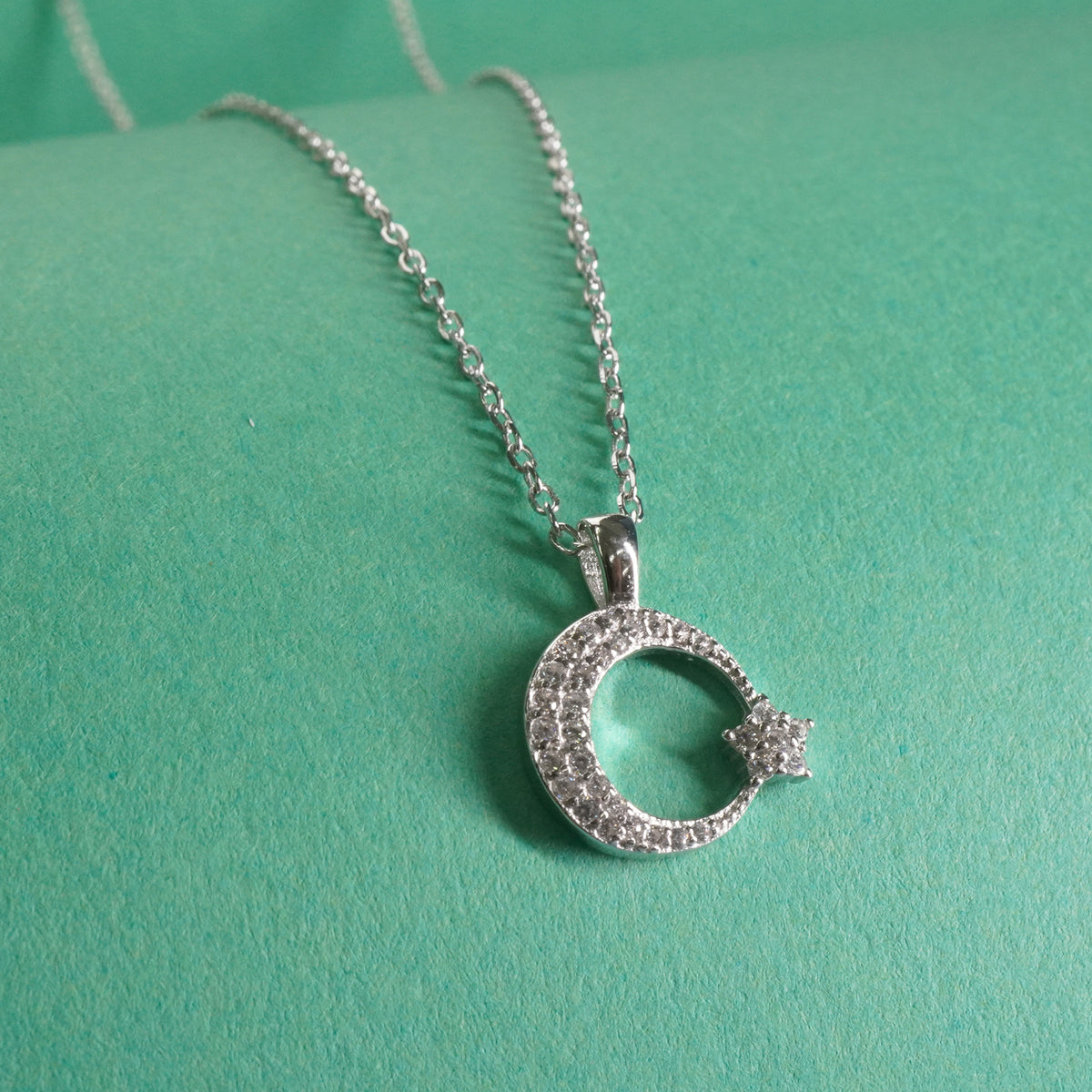 sterling Silver necklace with a crescent moon pendant on a green background