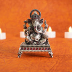 Decorative statue of ganpataji on an orange background with candles